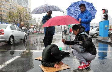 青岛一老人路上摔倒 众人雨中撑伞