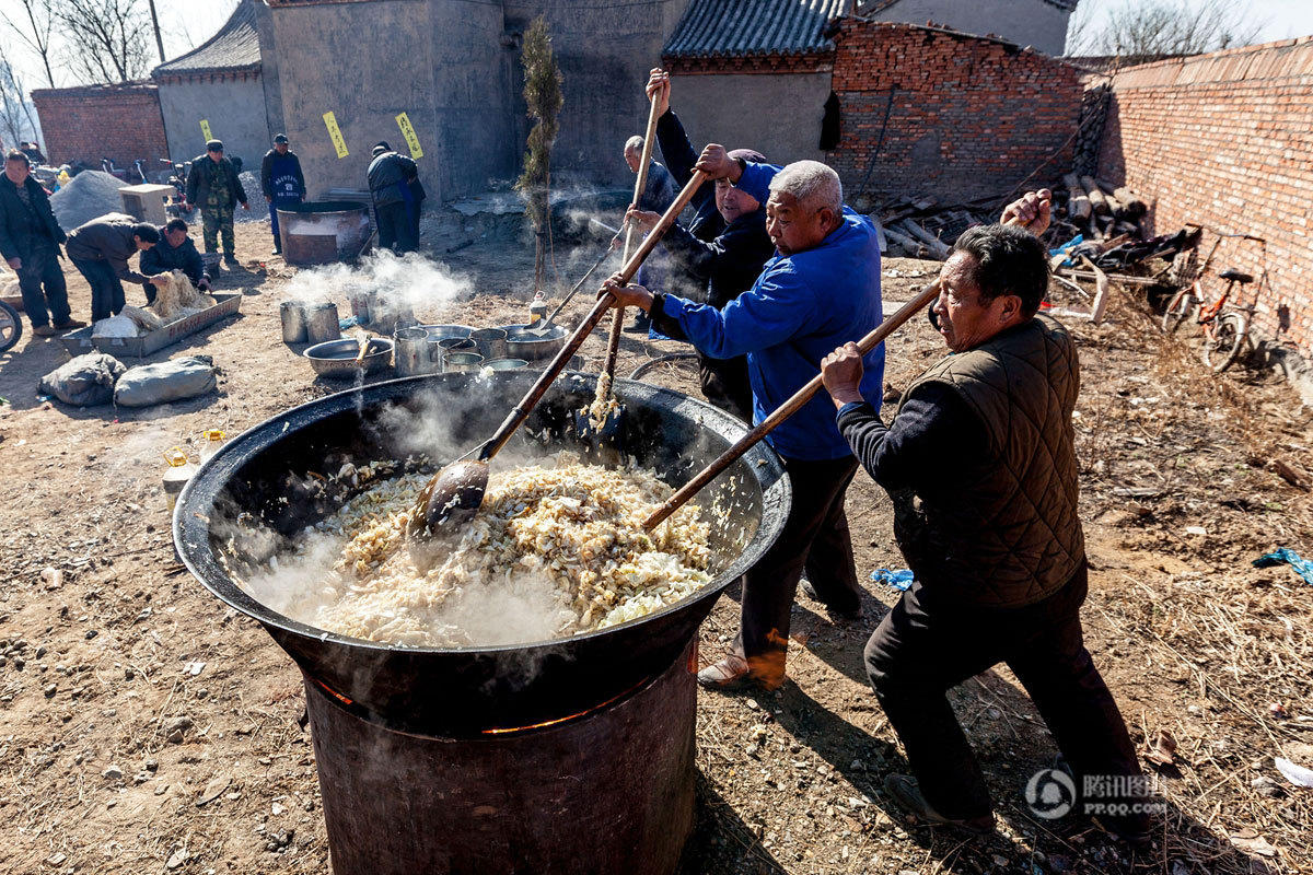 　　到了中午，庙上支起大锅做饭，供香客和赶庙会人员免费食用。图为厨师在炒菜。