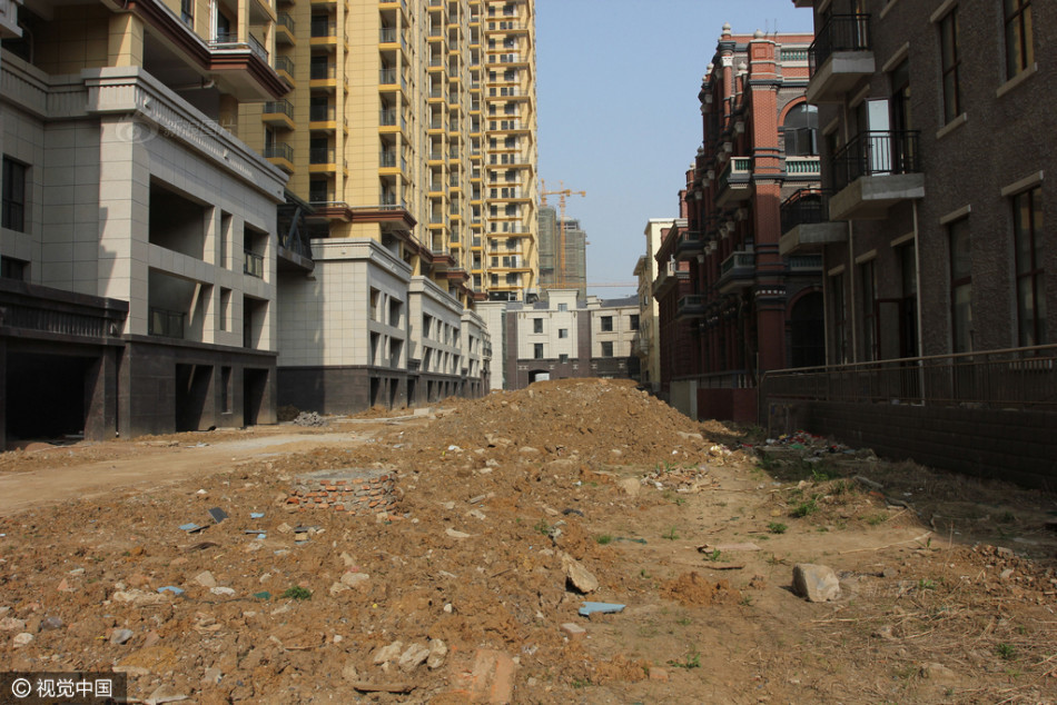 汉口印象楼盘工地，3栋30多层高楼主体工程已建成，但各单元门均已上锁，小区道路上堆着渣土、管材，绿化施工还没开始，现场冷冷清清，没有一名施工人员。