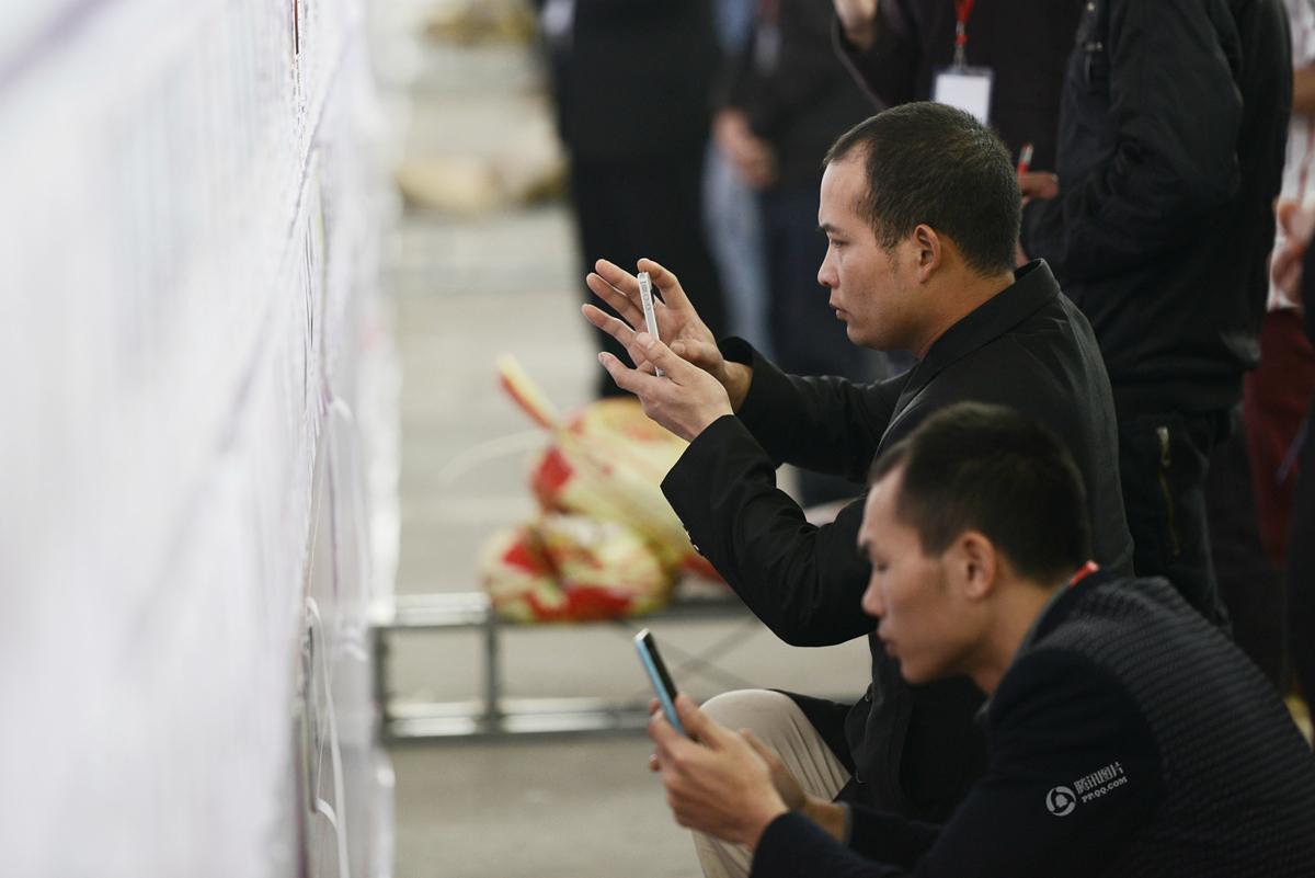 　　相亲者们在相亲墙前拍下心仪对象的资料。