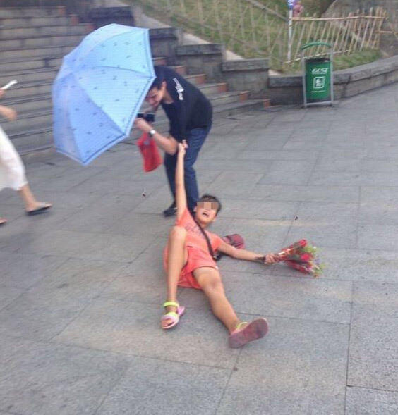 卖花女躺在地上，不让男子离开。