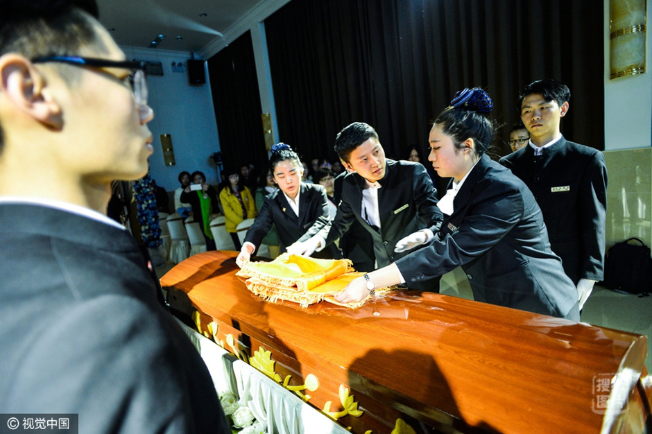 据报道，在韩国，抑郁症患者与轻生者人数近些年来不断增加，为此首尔孝元治疗中心提出了“死亡体验”的治疗方案，希望人们在经历过“死亡”后学会感激生活，享受生活。接受治疗的人来自各个阶层，包括迫于学业压力的青年、空巢老人以及担心给子女增加经济负担的老年人。他们身穿白色长袍坐在排列整齐的木棺中与康复中心负责人进行简短的交谈，拍遗照，写信告别并大声读出遗言。图为天津殡仪服务中心的工作人员为体验者带来一场模拟的遗体告别仪式。