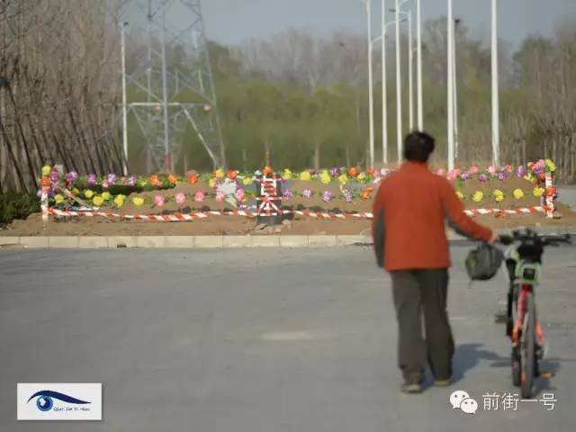 　　记者看到，附近并排有较多建成高楼，但几乎都无人入住，过往行人很少。门口共有两条并排东西向马路，该处坟地挨着中间绿化带，占据南侧三分之二路宽的马路。