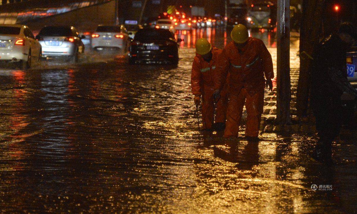 　　沈阳市区道路积水，环卫工检查下水道。