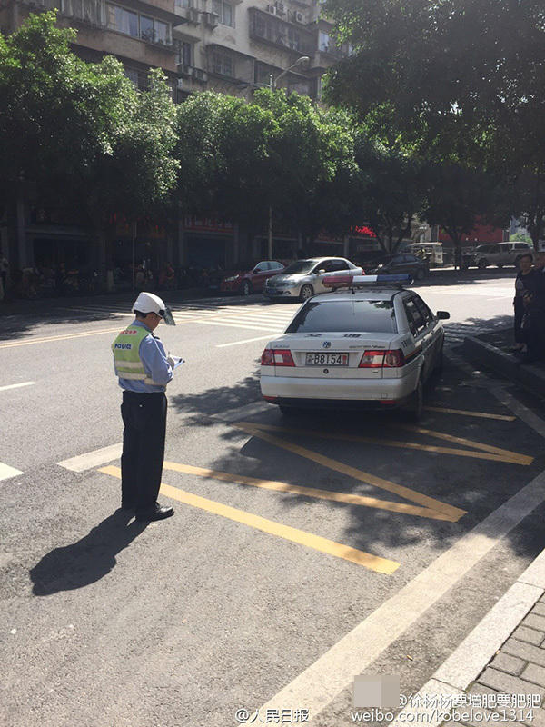 　　图为交警在对违停的警车开罚单。
