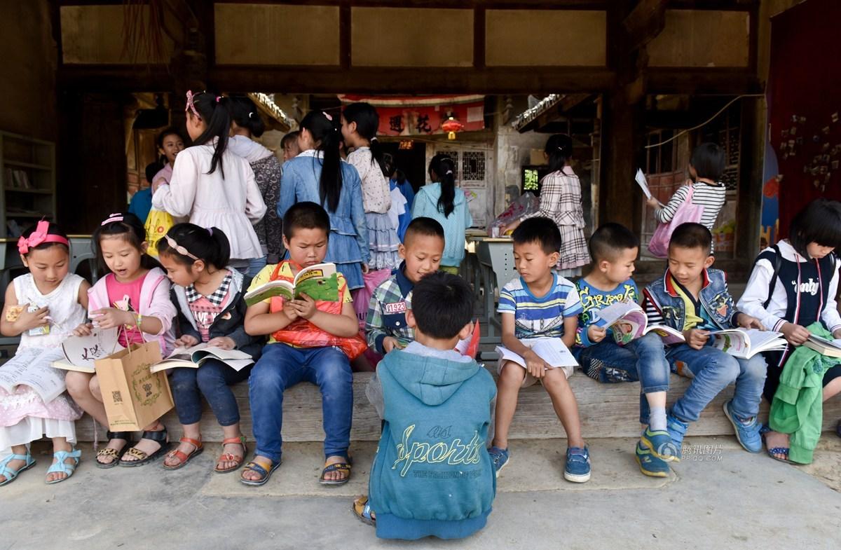　　孩子们从书架上挑选自己喜欢的书籍，然后一字排开地坐在门槛上认真看起书来。