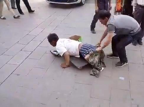 　　画面中，该名假乞丐似乎失去一双小腿、躺在一块滑板上在街头行乞，要求路人施捨金钱。期间，一名穿灰色上衣的男子伸手捉摸乞丐的臀部，似在验证乞丐是否真的失去双腿。该名路人随即脱去假乞丐的外裤。