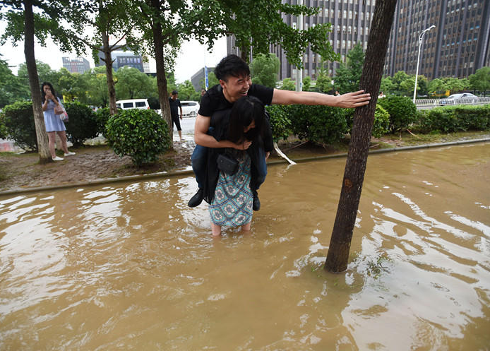 　　2016年07月04日，湖北省武汉市，光谷大道与金融港三路交叉口附近积水未全退，市民仍需脱鞋涉水过马路，一女子为不让男友湿鞋，执意要背着他过马路，尝试一下背男友的感觉。
