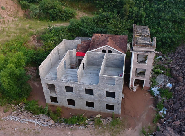 　　据屋主杨某介绍，他的房子建于90年代，2005年做过翻修，12年初因拆迁补偿问题与当地村委无法达成一致意见被断水断电。房屋由原来的最高处变成现在的“锅底”景观。期间杨某数次上访到市信访局要求恢复水电，保证他们一家人的基本生存权利，一直没有得到有效解决，期间由于工地在房子四面不停堆积土石方，为了刚出生的婴儿健康问题不得不搬出去租房住。