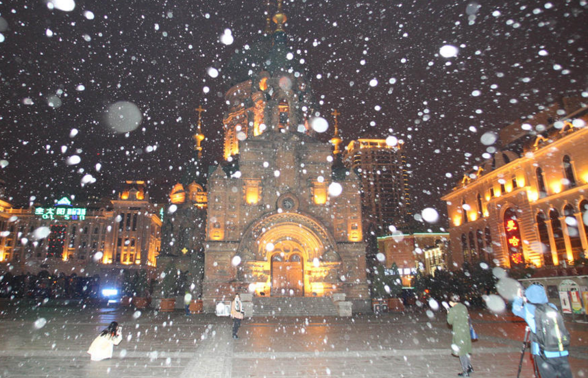 10月21日晚，哈尔滨市下起了小雪，部分雪花落地后融化成水。在各处景点，市民和游在雪中拍照。当天气温明显下降，气象部门发出道路结冰黄色预警。