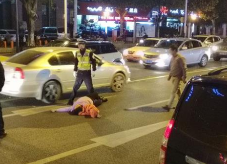 　　据现场目击者称，当时交警正在执勤，该五菱小面包由西向东方向驶过，在遭遇警方执法检查时，车上女子率先下来交涉，很快女子情绪激动起来，并推开民警直接奔向马路中央，就地躺卧翻滚，后面正常通行的白色轿车避让不及，刚好碾压到女子左脚，女子立即大声叫唤喊疼，引来众多市民围观。值得注意的是，女子躺倒在地后，同车的面包车司机（男）还下来试图将其拉起，可女子就是不听，不停哭闹翻滚。据现场执勤的三大队民警称，他们当时例行执法，可女子却认定他们是针对外地车牌，拒绝配合检查，女子操外地口音，沟通也不流畅。女子前后的表现，整个像一部闹剧！