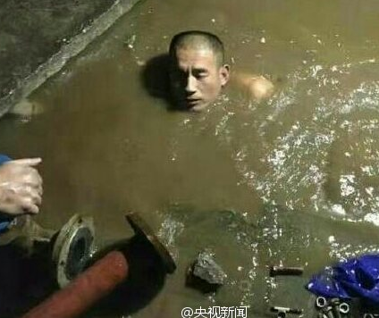 　　供热工人全身浸污水中更换阀门。