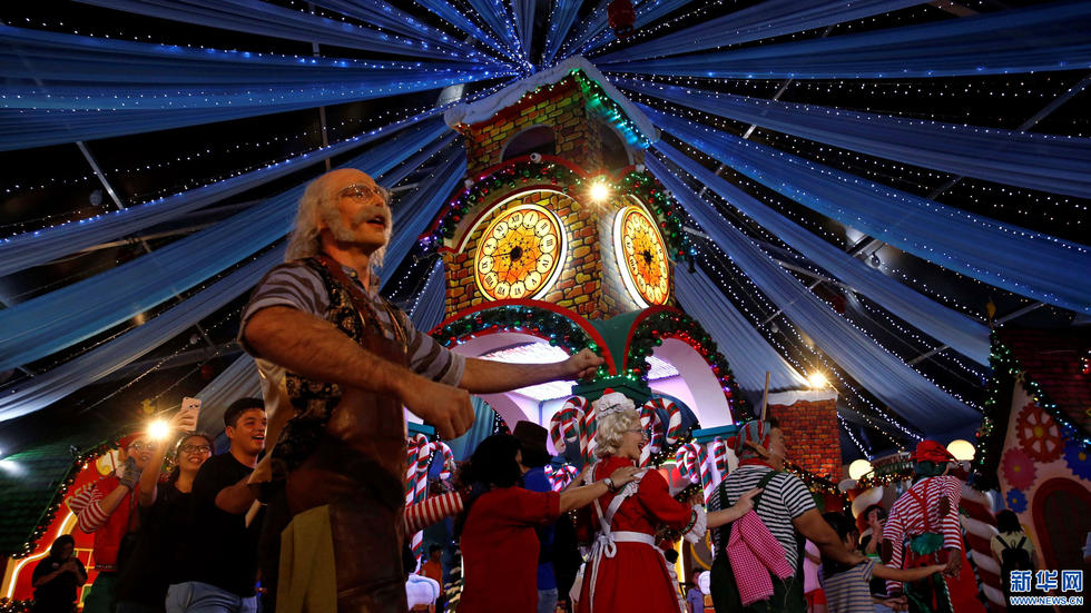 12月12日，人们在新加坡环球影城的圣诞灯饰景观中与表演者一起跳舞。