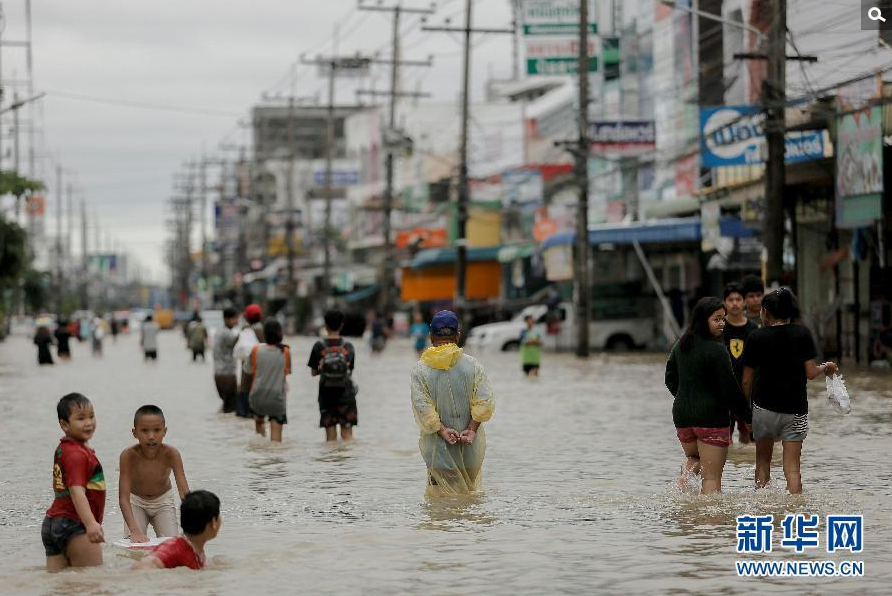 1月6日，在泰国南部受灾最严重的那空是贪玛叻府，人们在洪水泛滥的街上涉水而行。泰国内政部7日发布公报说，持续一周的暴雨已造成泰国南部10个府共约74万人受水灾影响，迄今导致至少12人死亡。泰国气象局7日预报说，暴雨还将持续至少两天。