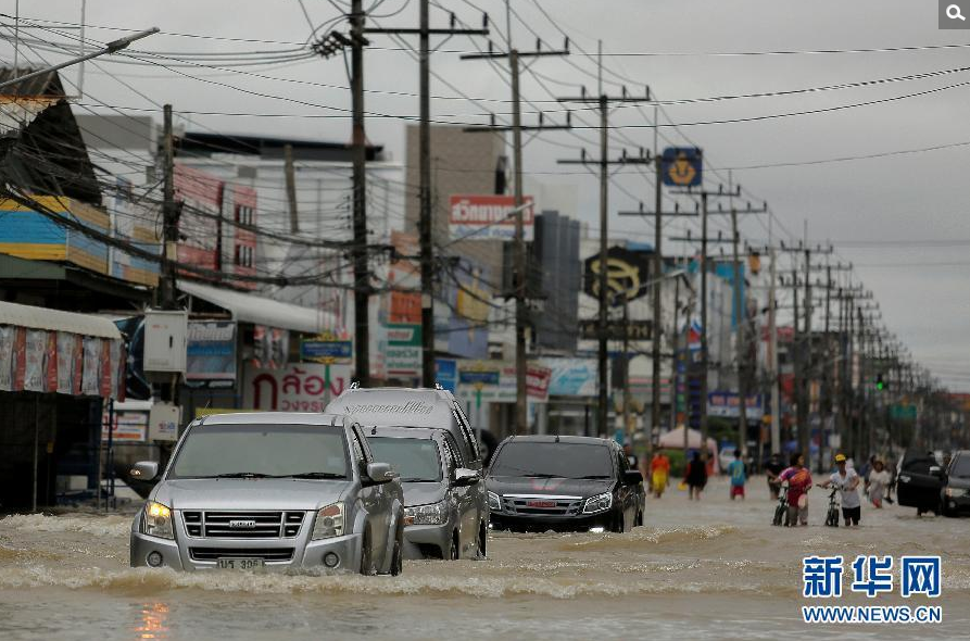 1月6日，在泰国南部受灾最严重的那空是贪玛叻府，汽车从洪水泛滥的街上驶过。