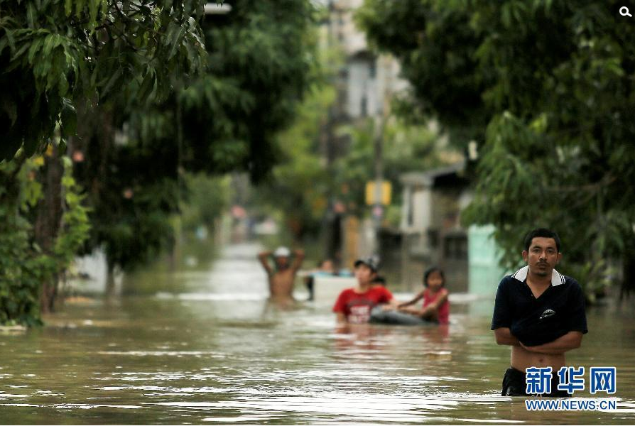 1月6日，在泰国南部受灾最严重的那空是贪玛叻府，人们在洪水泛滥的街上涉水而行。