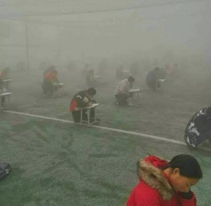 　　投诉人闫先生给记者发来两张照片，照片显示，天气灰蒙蒙的，在一个露天的足球场上，很多学生半蹲着趴在凳子上做卷子，由于雾霾太大，第2排后面的学生身影已经很模糊。20日下午3时50分左右，大河报记者赶到林州，当地的空气雾霾十分严重，能见度只有二三百米。在临淇镇一中学校附近，记者见到了闫先生。他告诉记者，现在学校已经知道记者要来采访了，临时放假了，考试也取消了。随后，在校门口，该校八年级的一名学生告诉记者，学校确实确实在12月19日考试了，上午考英语和数学，下午考语文和物理。该学生告诉记者，八年级共十个班，每个班六七十人，大家都参加了考试，“在操场上考的，搬着凳子在外面”。