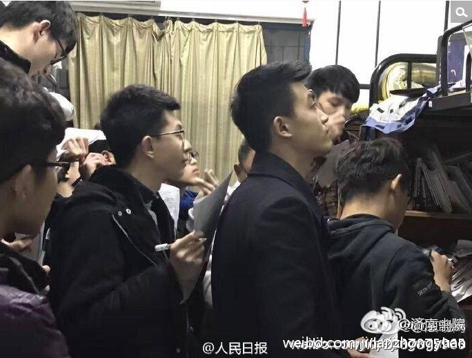 　　一群男生拿笔记本听课。