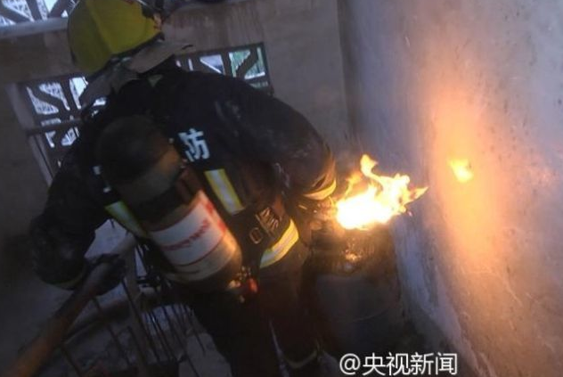 　　此时，消防员程其民自告奋勇，抱起有1米高火焰的煤气罐就往楼下跑。