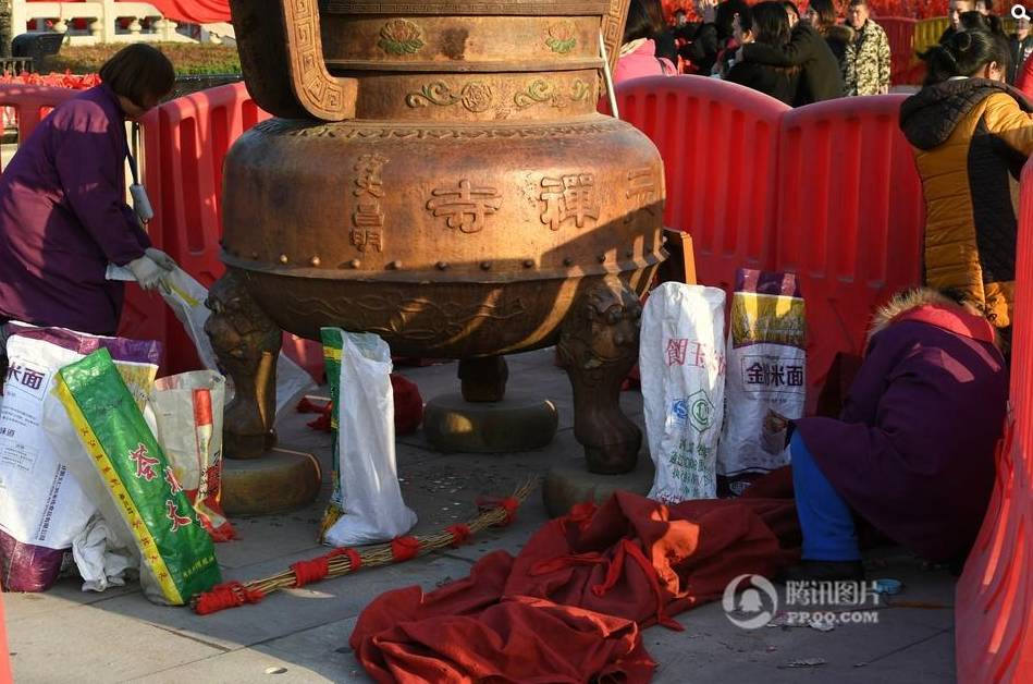 寺庙的工作人员在清理香客扔在庙里的硬币及纸币。